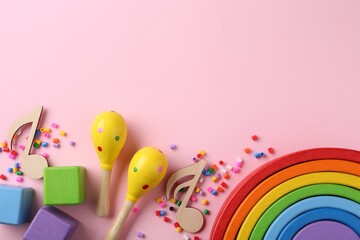 Baby song concept. Wooden notes, kids maracas and toys on pink background, flat lay. Space for text