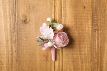 Fototapeta na wymiar Stylish pink boutonniere on wooden table, top view