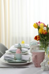Fototapeta na wymiar Easter celebration. Festive table setting with beautiful flowers and painted eggs