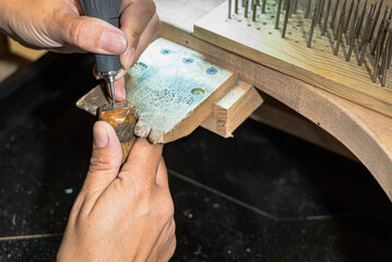Jeweler drilling small holes before stone setting in metal pendant