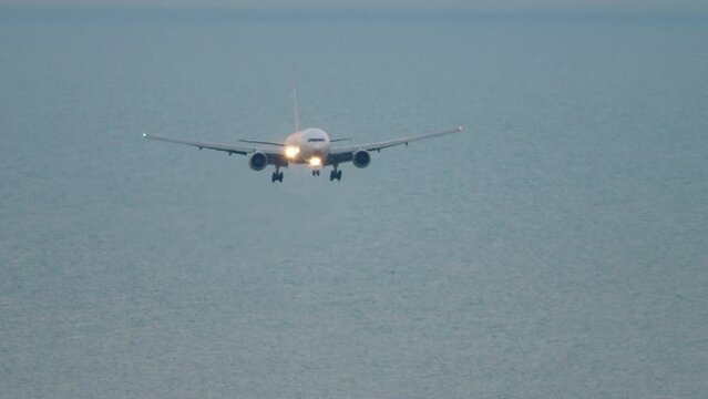 Widebody aircraft landing. Plane flies, front view. Airplane with headlights is approaching. Tourism and travel concept