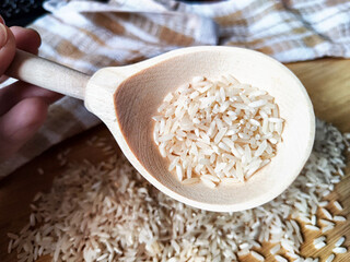 Rice scattered on textured fabric and in a wooden spoon. Grits for cooking. Texture, background, copy space and place for text