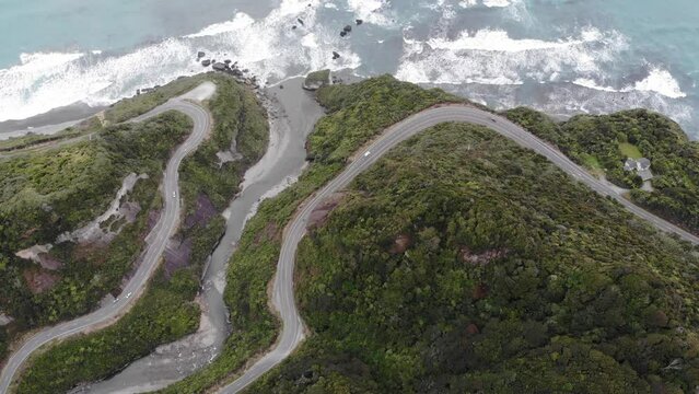 aerial panorama of the west coast of new zealand south island; winding road next to turquois water, mighty cliffs and little islands, ten mile creek near greymouth and paparoa national park