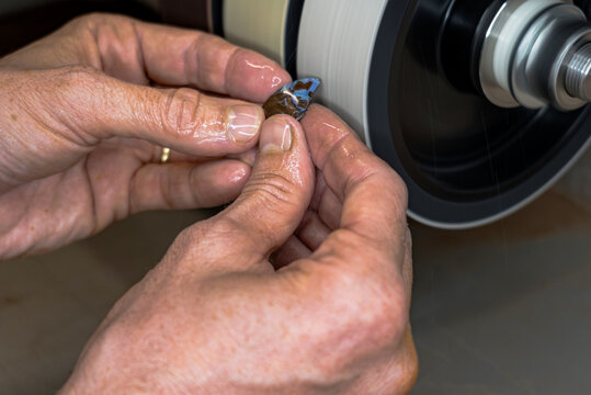 Craftsman cutting blue opal stone into the cabochon shape