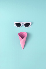 Summer creative concept pink cornet with white sunglasses on pastel background. Minimal ice cream idea.