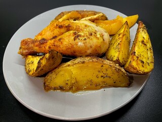 Baked potatoes and chicken in curry sauce on a gray plate