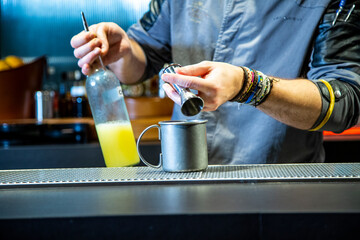 Barman prepara cocktail de piña colada sobre la barra de un cocktail bar nocturno close up con detalles exclusivos