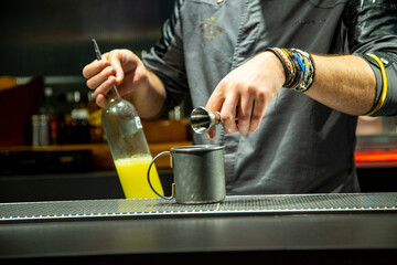 Barman prepara cocktail de piña colada sobre la barra de un cocktail bar nocturno close up con detalles exclusivos