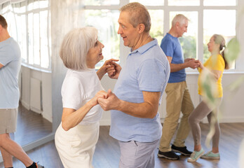 Couple of elderly man and elderly woman dancing waltz in studio