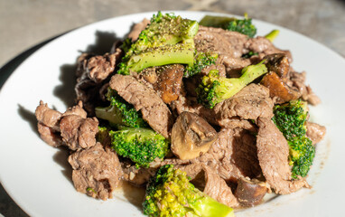Bong cai xao thit bo. Vietnamese beef stir fried with green broccoli on white background. Beef is well marinated with salt, black pepper, chopped onion. Then green broccoli and mushroom is added