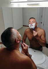 Shirtless man shaving