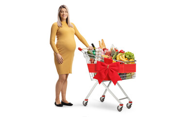 Pregnant woman standing with a shopping cart full of groceries tied with a red ribbon