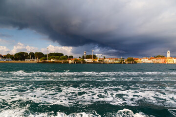 Obraz premium Sant'Elena and San Pietro di Castello island at extreme east end of sestiere of Castello in Venice, Italy. View from Venetian lagoon in stormy weather with dark cloudy sky in background
