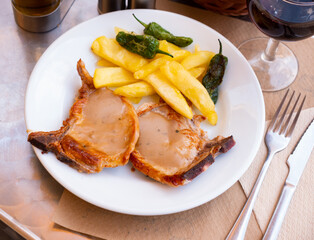 Roasted pork steak with sauce and vegetable garnish of potatoes and roasted pepper