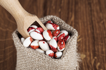 white beans with red spots in bags on a wooden table