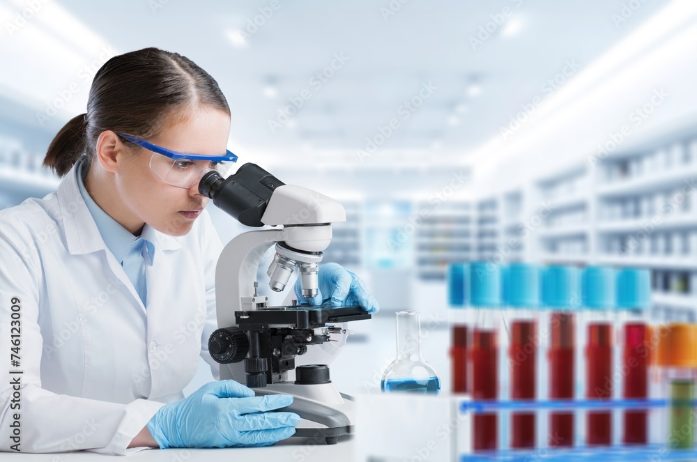 Wall mural Female scientist using a microscope in office