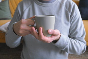 man no face sitting on the floor at home, holding cup of coffee, cozy home lifestyle