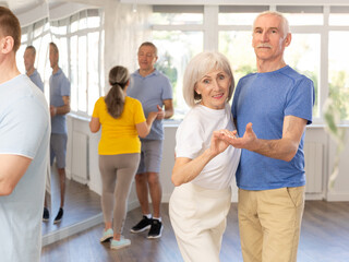 Mature man in dance hall with female partner and dances Latin rumba. Hobby, healthy lifestyle...