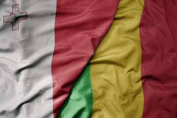 big waving national colorful flag of mali and national flag of malta.