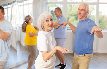 Group of elderly women and men in sportswear learn to dance the foxtrot in a choreographic studio