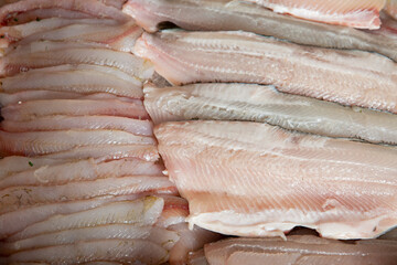 Fresh fish and seafood counter on market. White fish fillet close-up on display