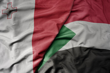 big waving national colorful flag of sudan and national flag of malta.