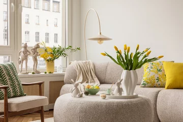 Tuinposter Interior design of spring living room with design sofa, furniture, vase with tulips, easter decorations, pillows and personal accessories. Home decor. Template. Easter holidays. © FollowTheFlow