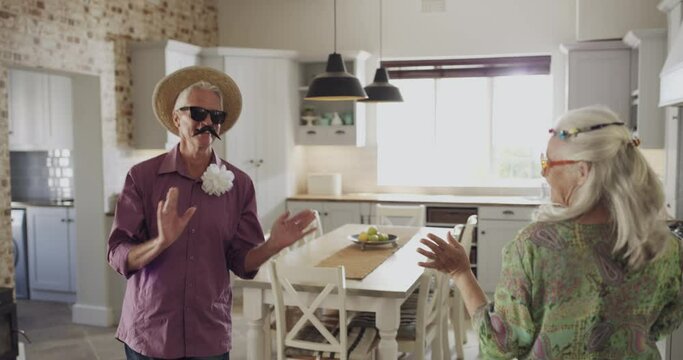 Dance, playing and a silly senior couple in the house for comedy, crazy and humor together. Happy, excited and a man and woman in retirement being funny, laughing and bonding with music and goofy
