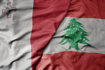 big waving national colorful flag of lebanon and national flag of malta.