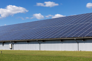 Halle mit Photovoltaik-Anlage, Solarzellen auf dem Dach in einem Gewerbegebiet in Niebüll, Schleswig-Holstein. An der Wand eine Wärmepumpe.