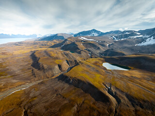 drone shot for breathtaking footage of wild nature in svalbard, majestic mountains in the clouds, freezing weather in svalbard, nature under the clouds, useful for newspapers and magazines, travel  © Dominik