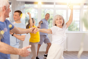 Elderly men and wome learn energetic twist dance in choreography studio