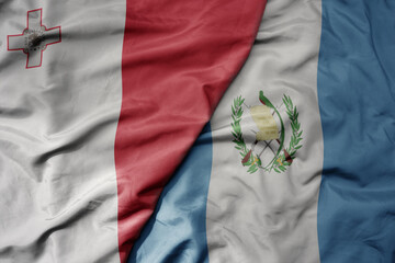 big waving national colorful flag of guatemala and national flag of malta.