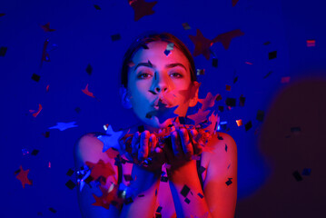 Happy Birthday. Studio portrait of girl blowing confetti. Confetti for birthday or valentines day. Sexy model blow confetti on birthday. Sensual woman celebrating birthday wit confetti.