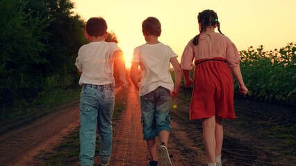 Kids play, run through field of sunflowers, friends run at sunset. Happy Children dream concept....