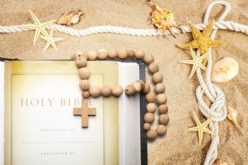 Bible book, wooden cross on sandy beach