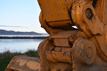 Large excavator bucket attachment point with beautiful bay background.