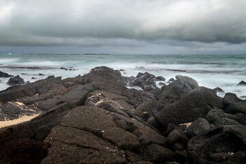 Long exposure with some iguanas resting on the volcanic rocks of a beach. Isabela Island, Galapagos.