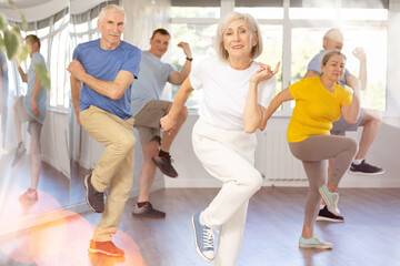 Cheerful elderly woman attending group choreography class, learning modern dynamic dances. Concept...