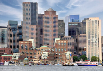 Colorful cityscape of Boston skyline and waterfront with tall modern buildings, boats anchored in...