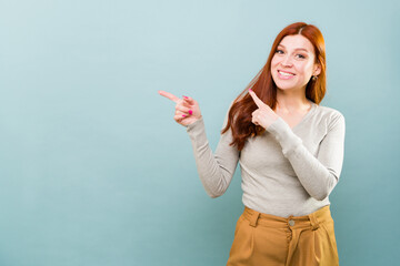 Cheerful caucasian woman looking happy pointing to an ad