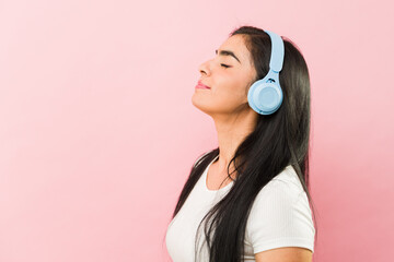 Profile of a happy latin woman with headphones listening to music