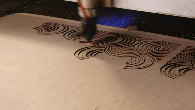 Timelapse Industrial laser is cutting a pattern on a plywood sheet