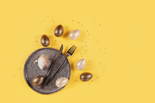 Table place setting and festive decor on yellow background. Easter eggs. Happy easter greeting or invitation card. Top view, flat lay, copy space for text