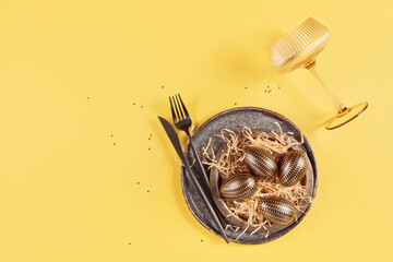 Table place setting and festive easter decor on yellow background. Happy easter greeting or invitation card. Top view, flat lay, copy space for text