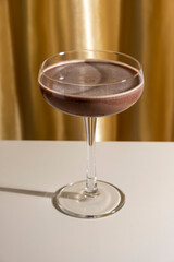 Espresso or chocolate martini cocktail on golden background