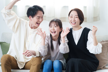 Fototapeta premium リビングでテレビを見て応援する親子