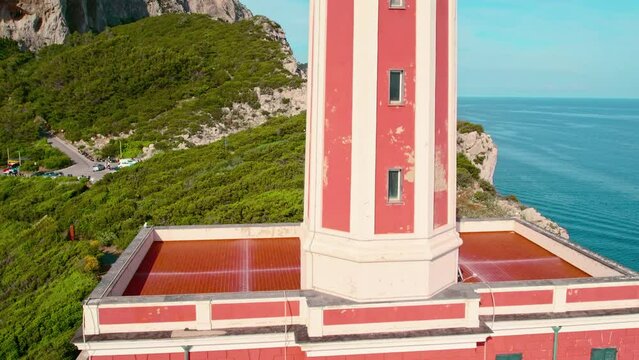 Close-up of a vibrant red lighthouse with green shutters. Aerial view of Faro di Punta Carena located on the island of Capri, Italy.