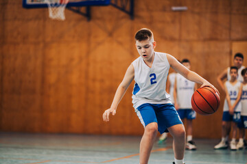 A junior basketball player in action dribbling a ball on court.