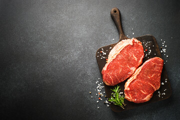 Fresh beef meat steaks on black.
